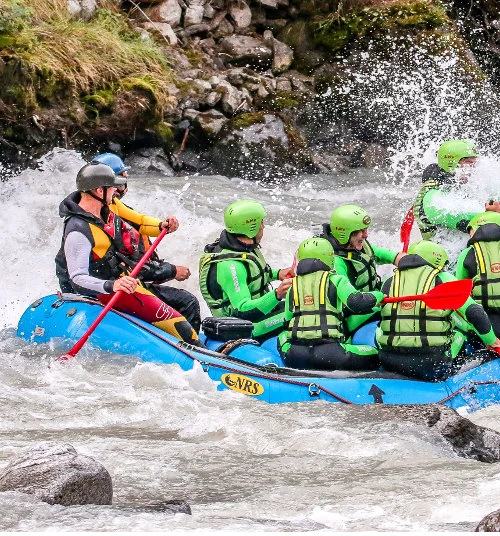Een groep mensen zit in een rubberboot om over een rivier te raften.